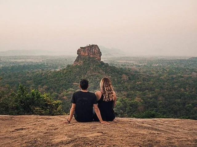 Paar sitzt auf dem Pidurangala-Felsen und blickt zum Sigiriya-Felsen