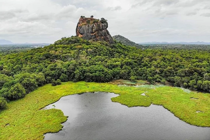 Sigiriya rock viewed from across a lake surrounded by green landscape
