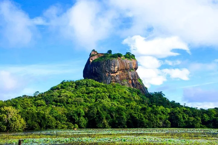 La roca de Sigiriya se alza sobre un bosque verde bajo un cielo azul